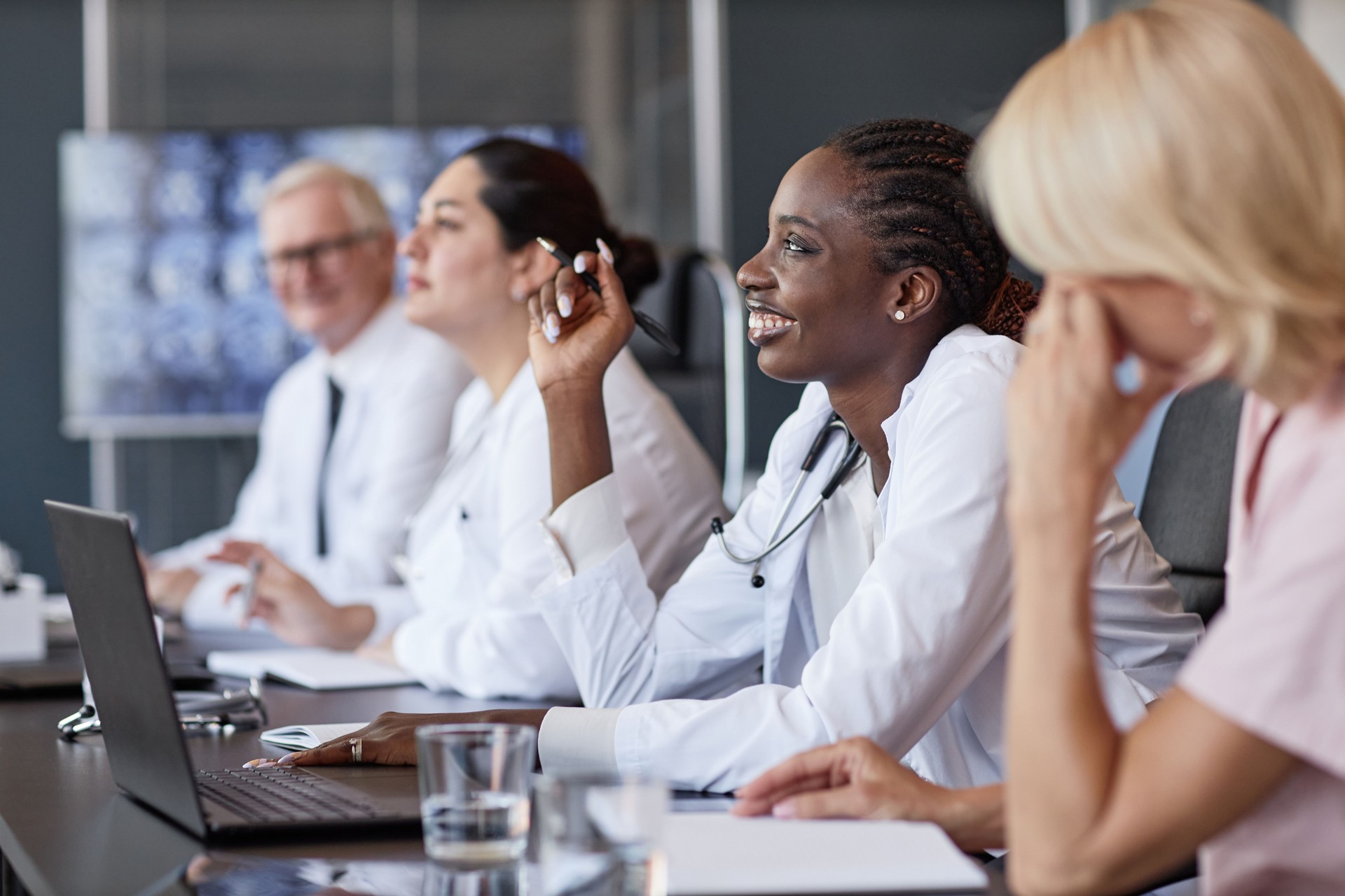 Smiling Black Woman Asking Speaker Question in Group Seminar with Colleagues in Office Room